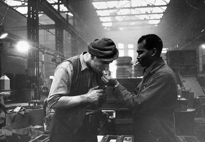 170.Thurston Hopkins - Lo sguardo umano della fotografia britannica 24 23.Kwessi Blankson dalla Giamaica offre una luce al collega Jake White presso la Phosphor Bronze Company gennaio 1955.A British Colour Conflict reportage Thurston Hopkins