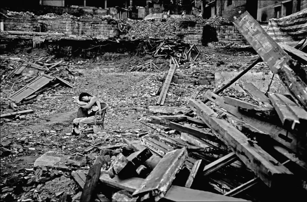 24.Donna che dorme su una sedia tra gli edifici in rovina in Cina
