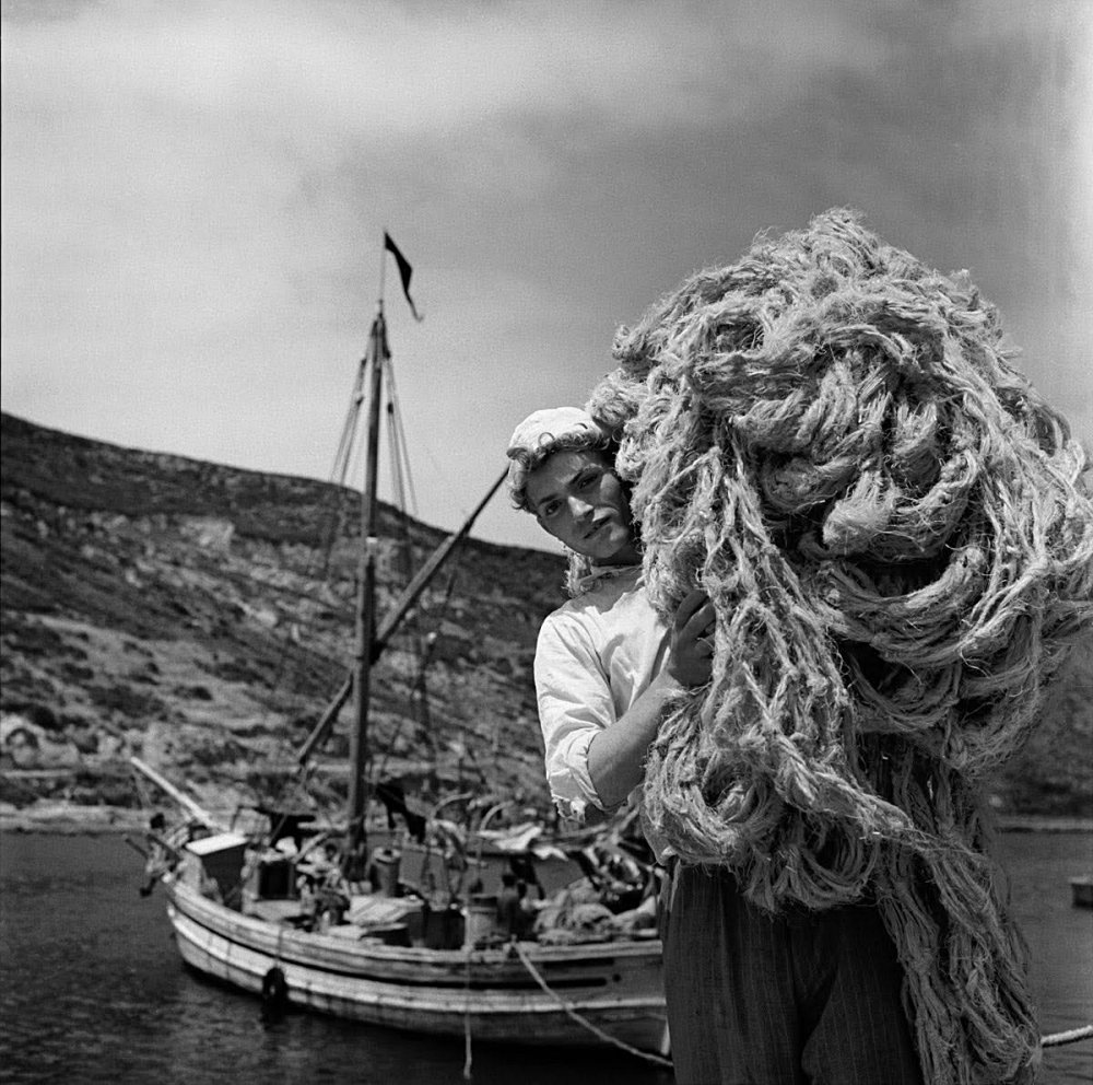 30.Un giovane pescatore che trasporta una grande quantita di corde o reti nel porto fluviale del Temo a Bosa. Sardegna 1956. Jean Dieuzaide