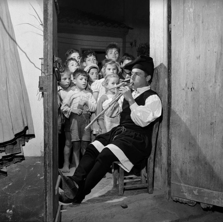 39.Musicista in costume tradizionale seduto sulla soglia di una porta a Cabras nella regione storica del Campidano di Oristano mentre suona le launeddas Sardegna 1956. Jean Dieuzaide