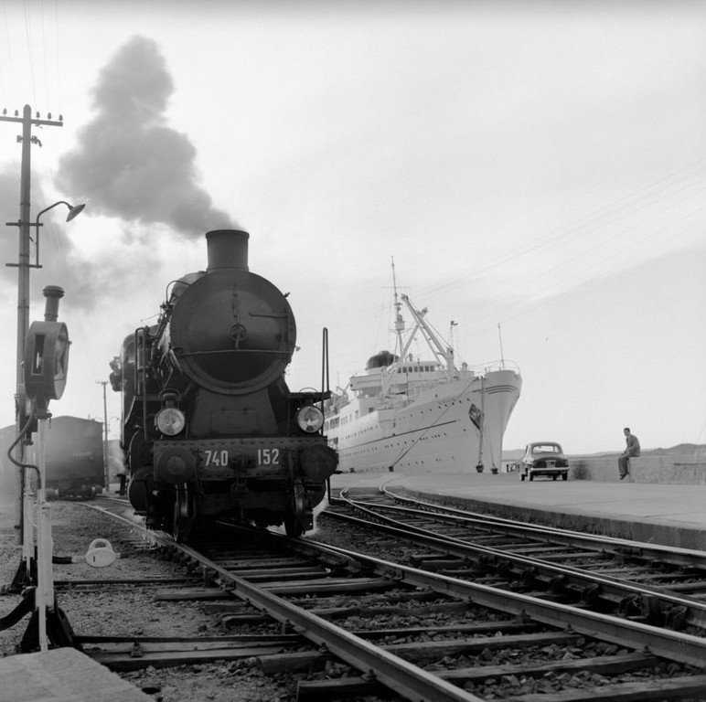 40.Una locomotiva a vapore in sosta sui binari vicino a una banchina portuale di Olbia. Sardegna 1956. Jean Dieuzaide